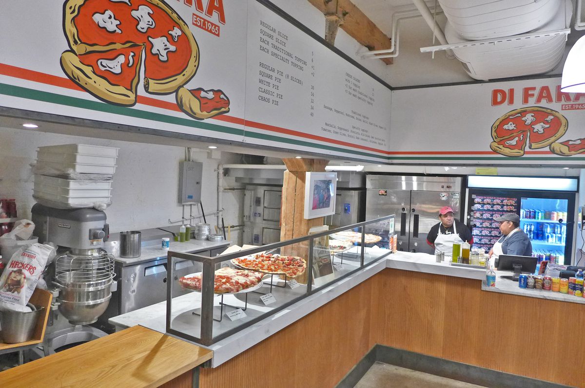 An L-shaped counter with pizzas displayed.