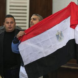 Mohamed Fahmy, a Canadian journalist of Al-Jazeera English, holds up an Egyptian flag after a retrial at a courthouse near Tora prison in Cairo, Egypt, Thursday, Feb. 12, 2015. An Egyptian judge ordered Fahmy and another Al-Jazeera English journalist, Baher Mohammed, released on bail Thursday as their retrial on terror-related charges continues. 