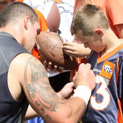 Broncos DE Derek Wolfe signs a young fans jersey after practice