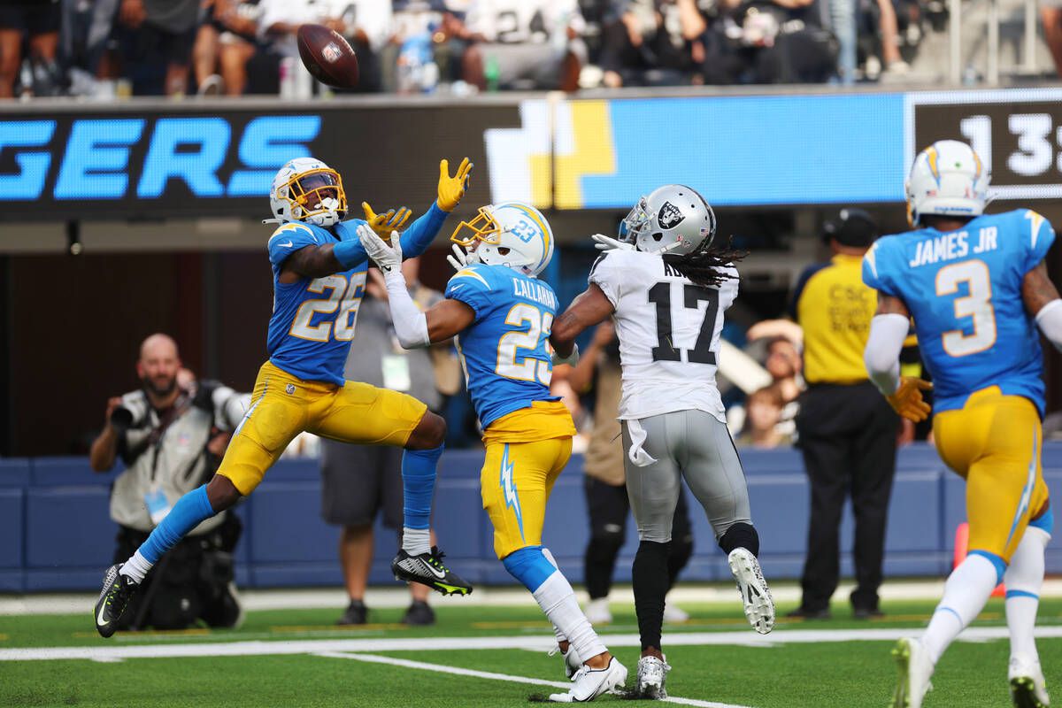 Los Angeles Chargers cornerback Asante Samuel Jr. (26) reaches for the ball for an interception as Raiders wide receiver Davante Adams (17) looks on during the second half of a NFL football game at SoFi Stadium in Inglewood, Calif., Sunday, Sept. 11, 2022.