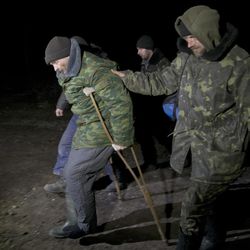 Ukrainian prisoners of war help an injured serviceman using crutches march before a prisoner exchange in separatist controlled territory, near Zholobok,  Ukraine, Saturday, Feb. 21, 2015. Ukrainian military and separatist representatives exchanged dozens of prisoners under cover of darkness at a remote frontline location Saturday evening. 139 Ukrainian troops and 52 rebels were exchanged, according to a separatist official overseeing the prisoner swap at a no man’s land location near the village of Zholobok, some 20 kilometers (12 miles) west of Luhansk. 
