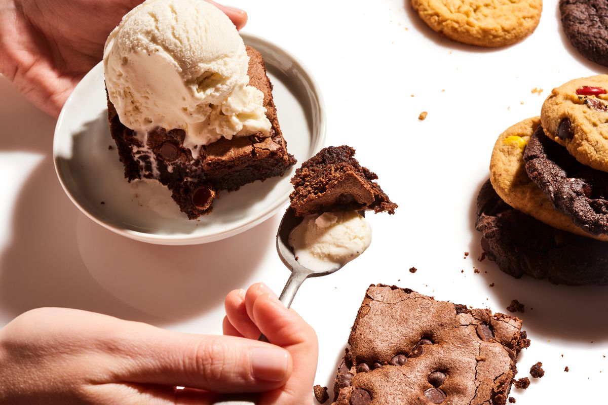 A hot fudge sundae with a brownie and a stack of cookies. 