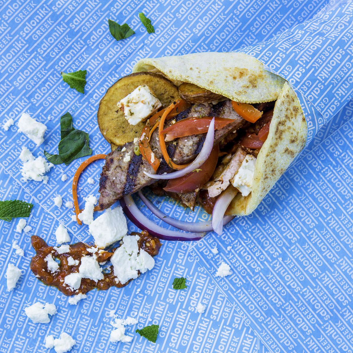 A pita sandwich filled with vegetables, chicken, and feta