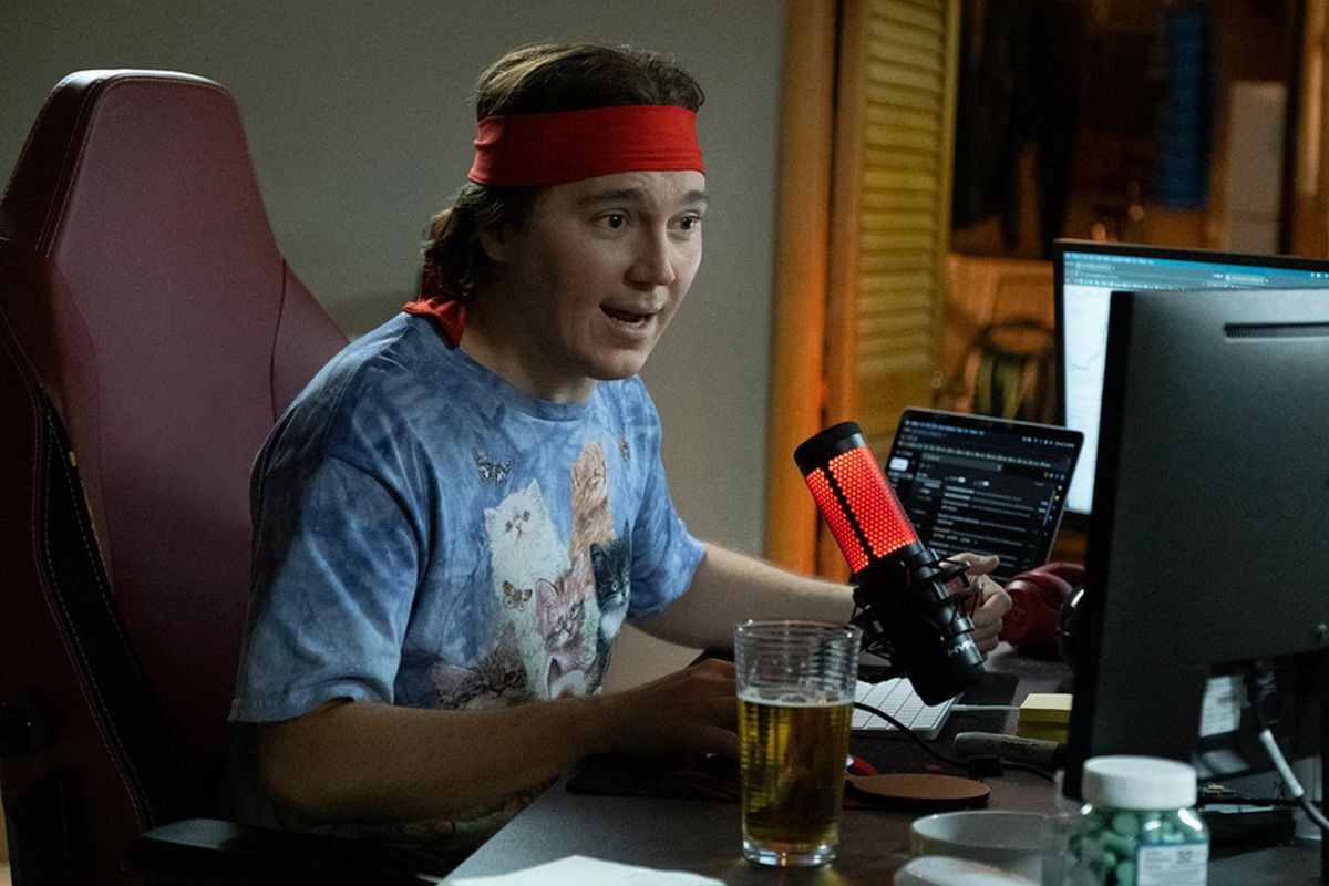 Paul Dano as Keith Gill, seated at his computer wearing a red headband.