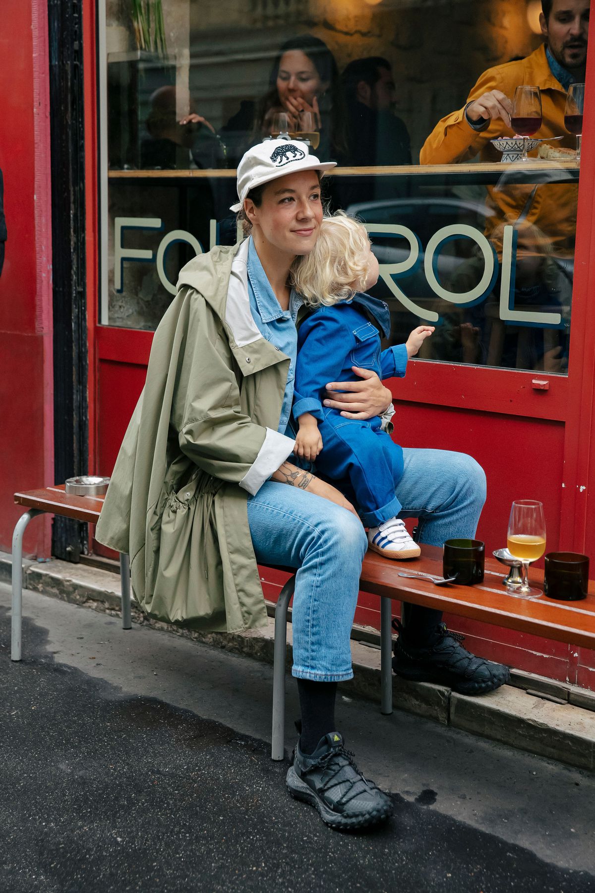 A woman cuddles her child on a bench in front of a wine bar.