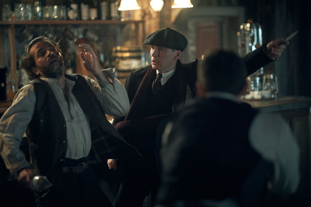 Cillian Murphy as Thomas “Tommy” Shelby slicing a man across the cheek with a switchblade in a bar in Peaky Blinders.
