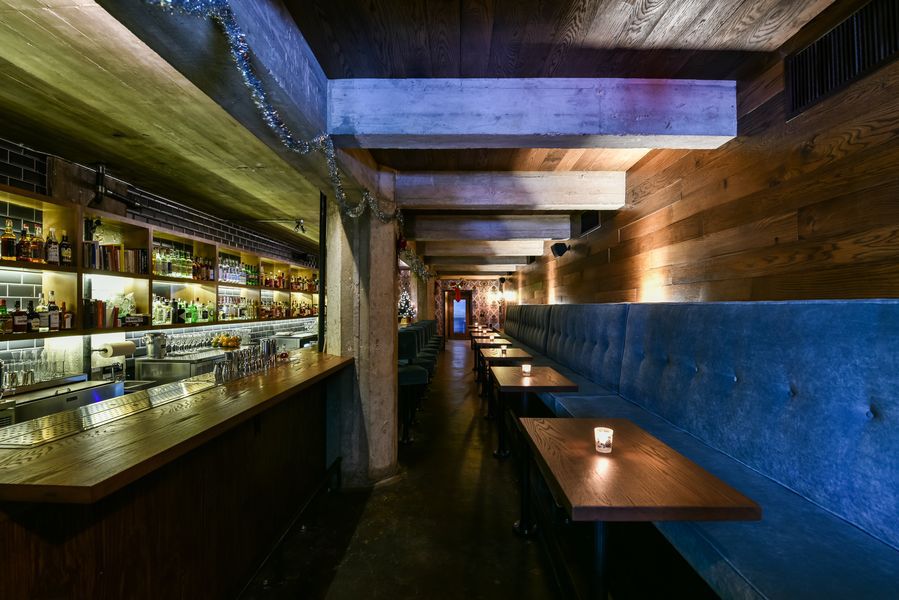 A bar with a bar top on the left and blue seating on the right.