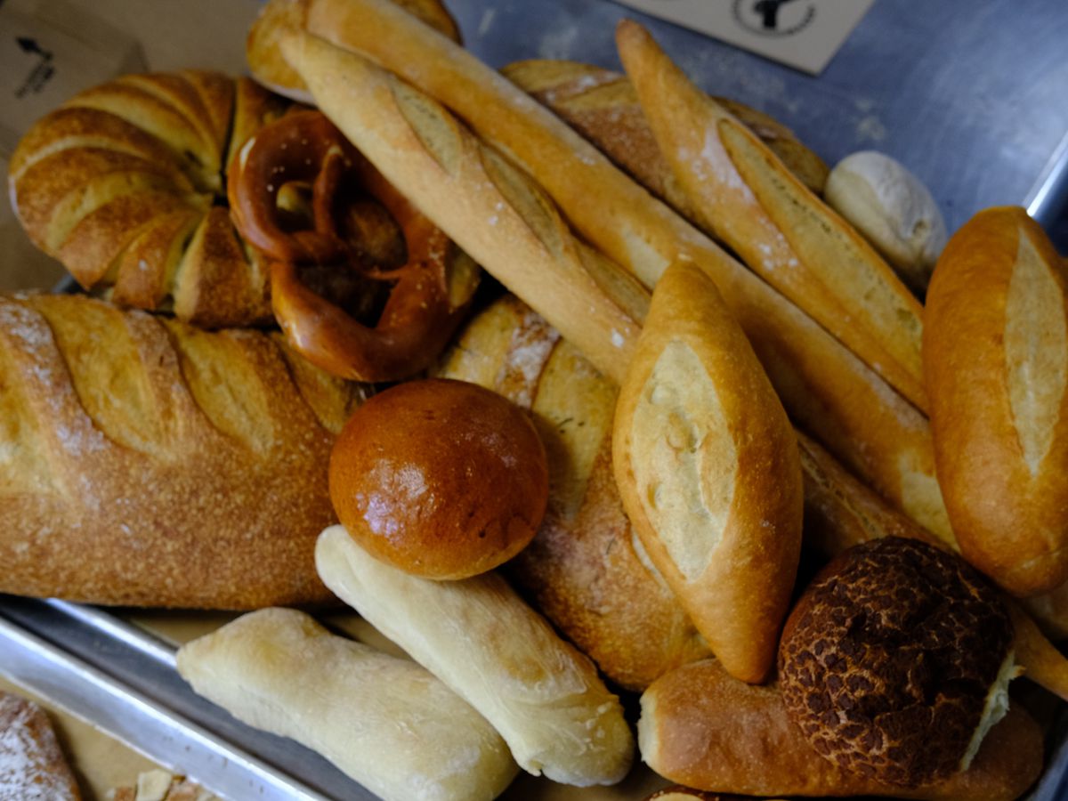 A tray of assorted baked goods, including baguettes, rounds, and rolls.