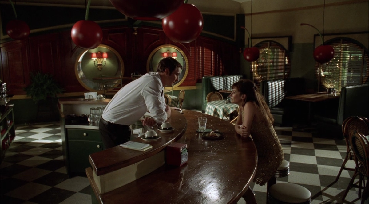 Chuck and Ned smiling at each other across a counter in the first episode of Pushing Daisies