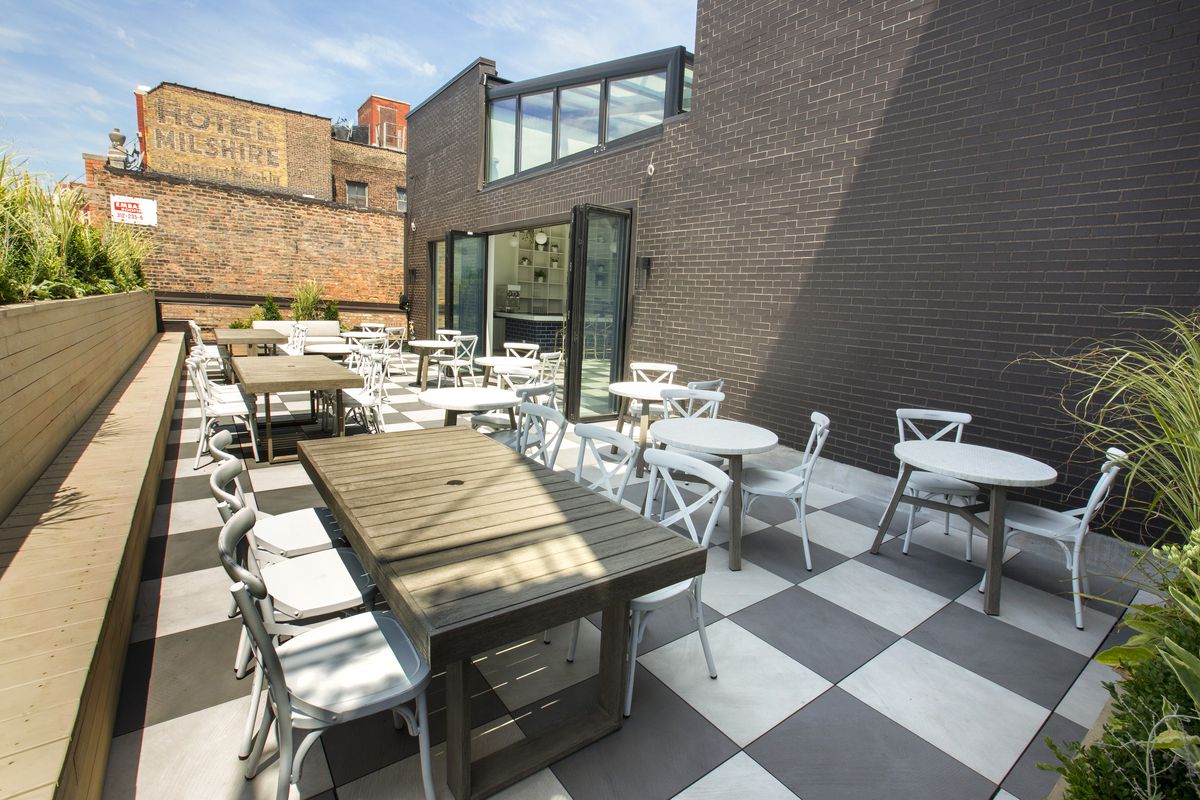 A rooftop patio dining space with a black-and-white checkerboard floor