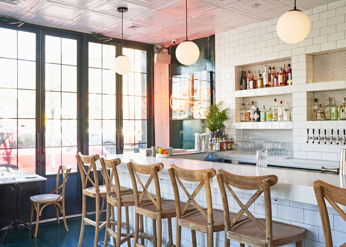 A white bar with wood stools fills Eyval in Bushwick.