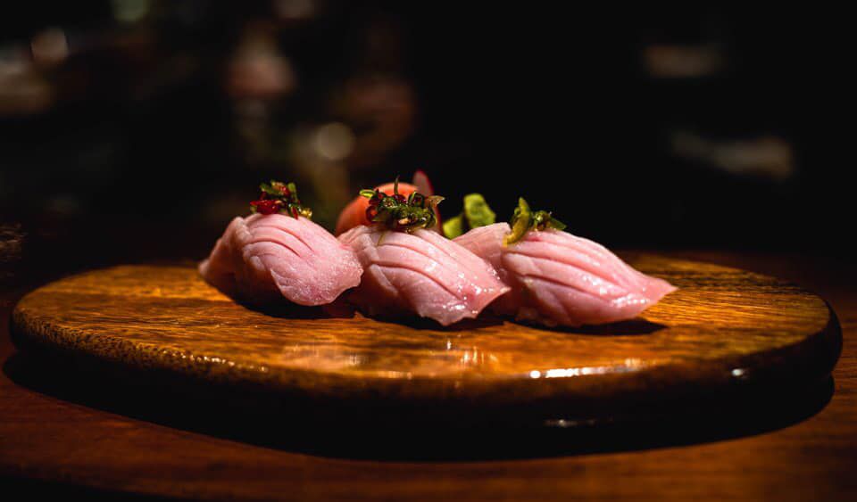 Three pieces of scored pink fish with delicate garnishes.