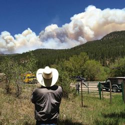 Tracy Bennett, ranch manager of Hidden Valley Ranch, a corporate retreat and guest ranch near Pecos, N.M., watches a large plume of smoke rise from a wildfire Friday, May 31, 2013. Bennett had to evacuate four guests the day before when the fast-moving fire in New Mexico's Santa Fe National Forest threatened the ranch and nearby cabins and vacation homes. 