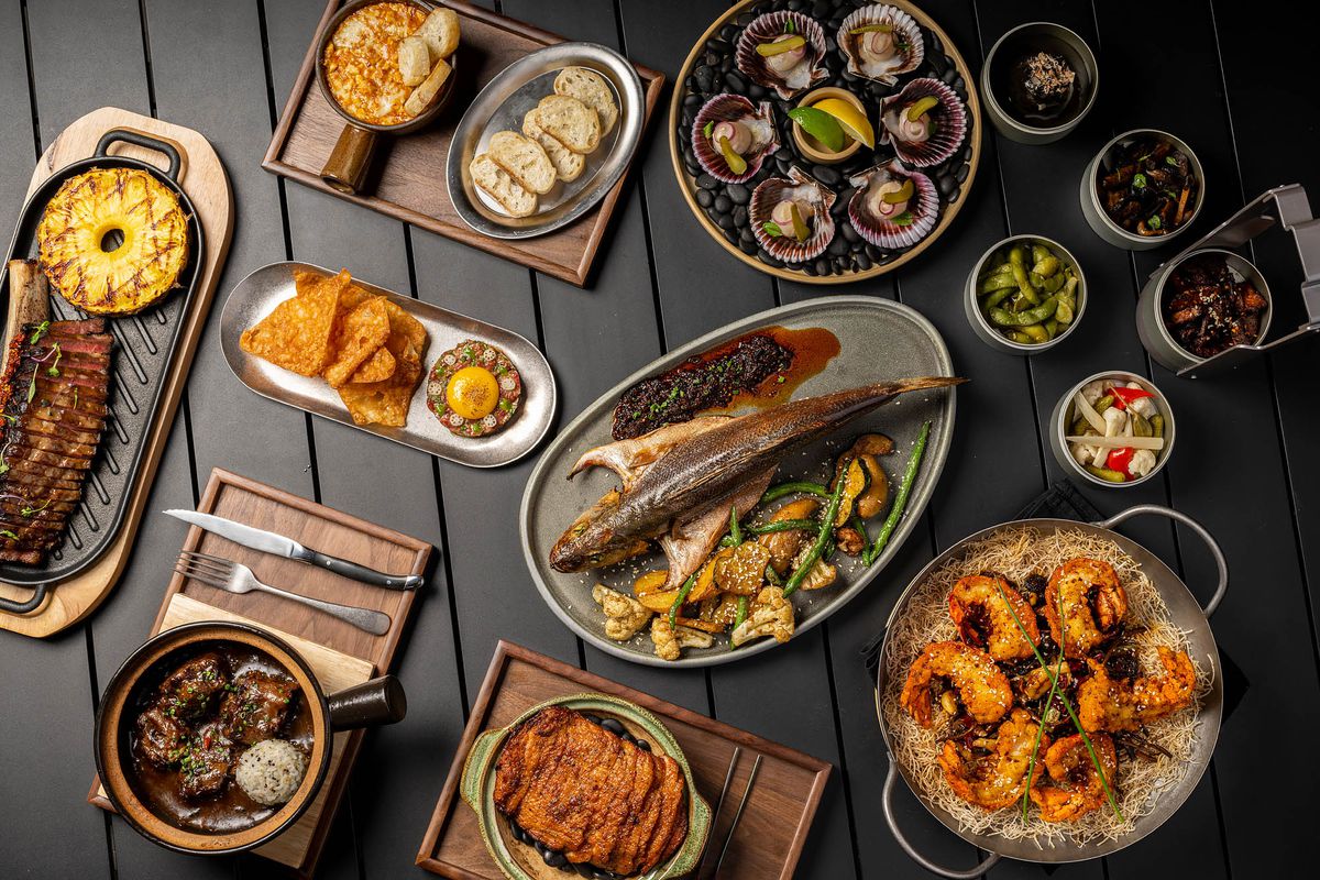 Modern Chinese dishes from a restaurant laid out against a black wooden table.
