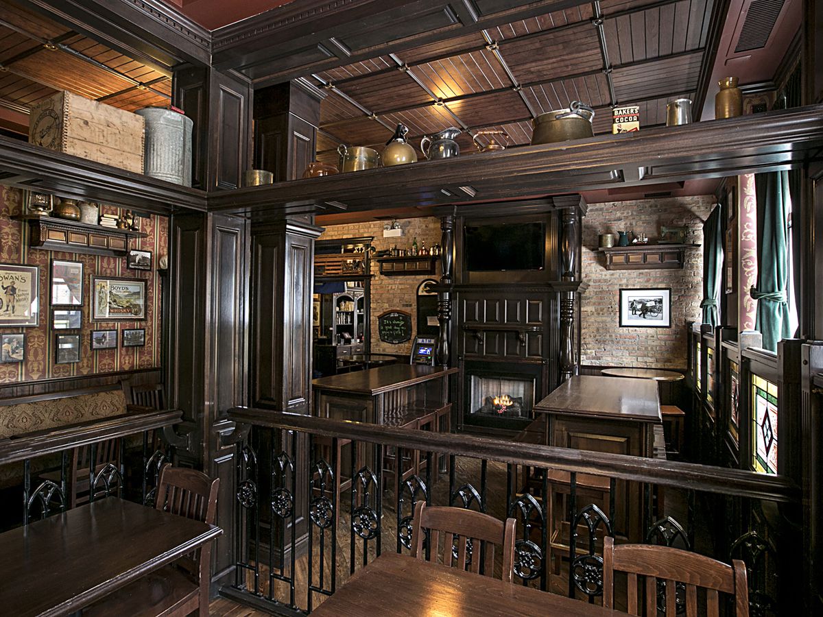 An interior shot of a dark wooded Irish bar. There are tables, chairs, and framed photos.