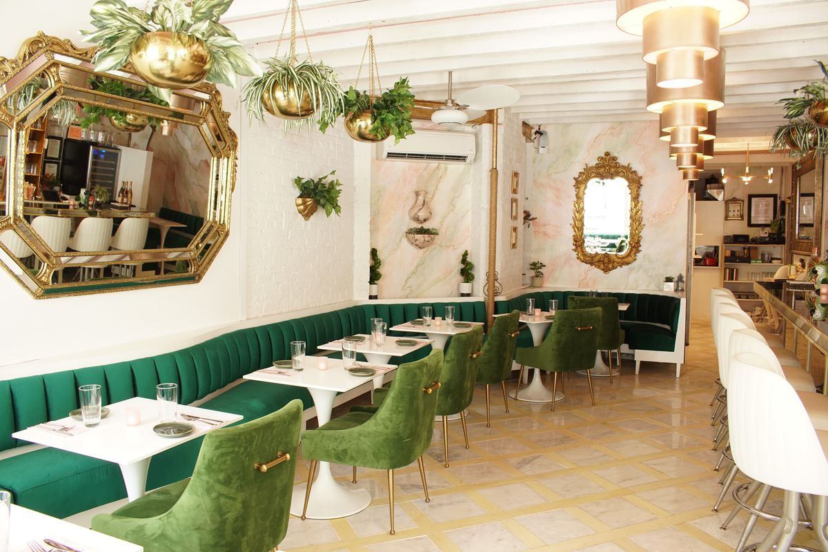 A white dining room with plants and a green banquette
