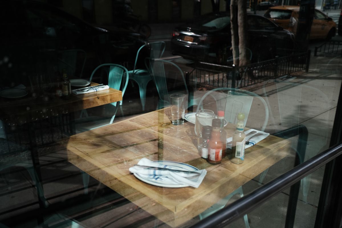 A table set with dinnerware and condiments can be seen through the glass window of a restaurant.