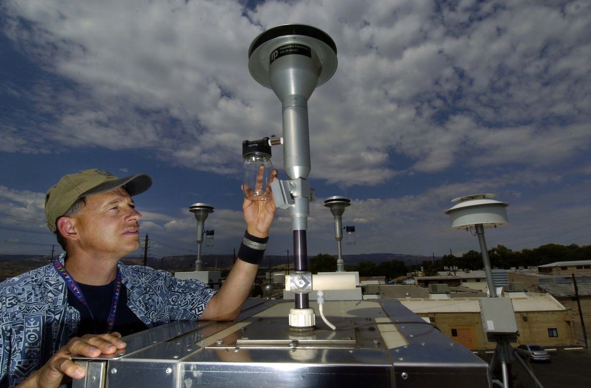 A person checking an air quality monitoring set-up outdoors.