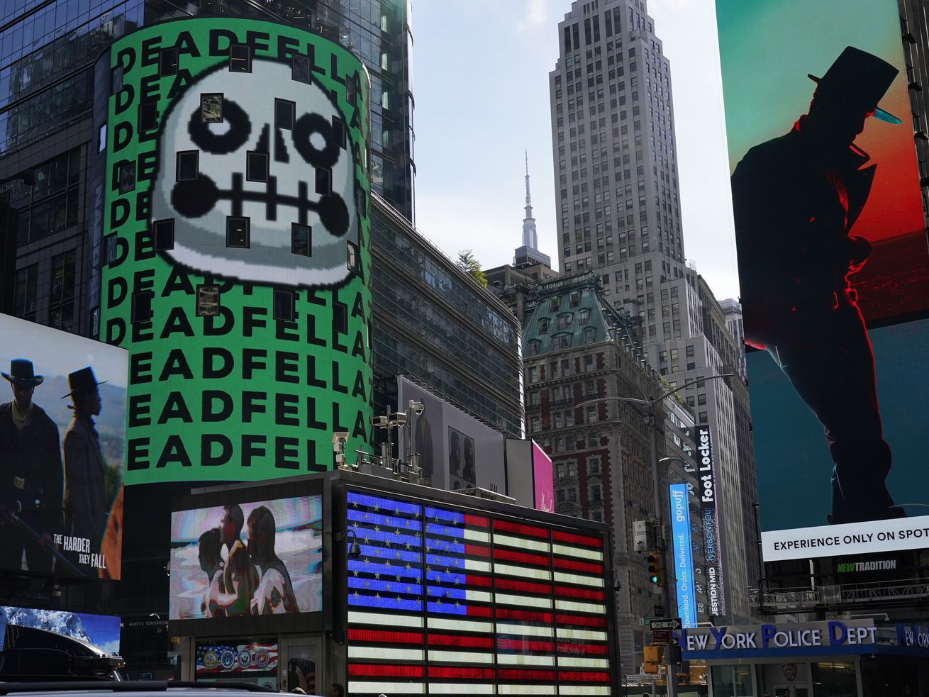 An image in Times Square above the neon American flag shows a picture of a grim cartoon skull and the repeated word “deadfella.”