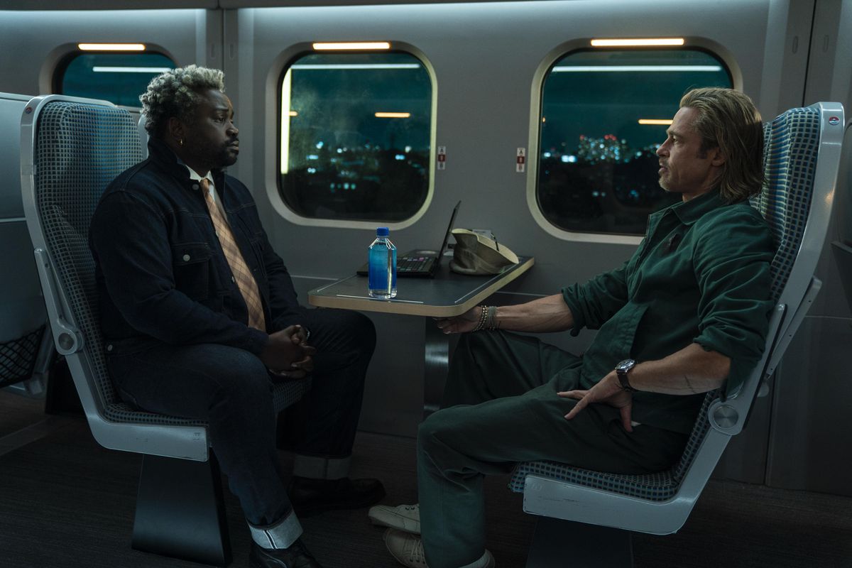 Lemon (Brian Tyree Henry) and Ladybug (Brad Pitt) sitting across from each other on a train and staring each other down in Bullet Train