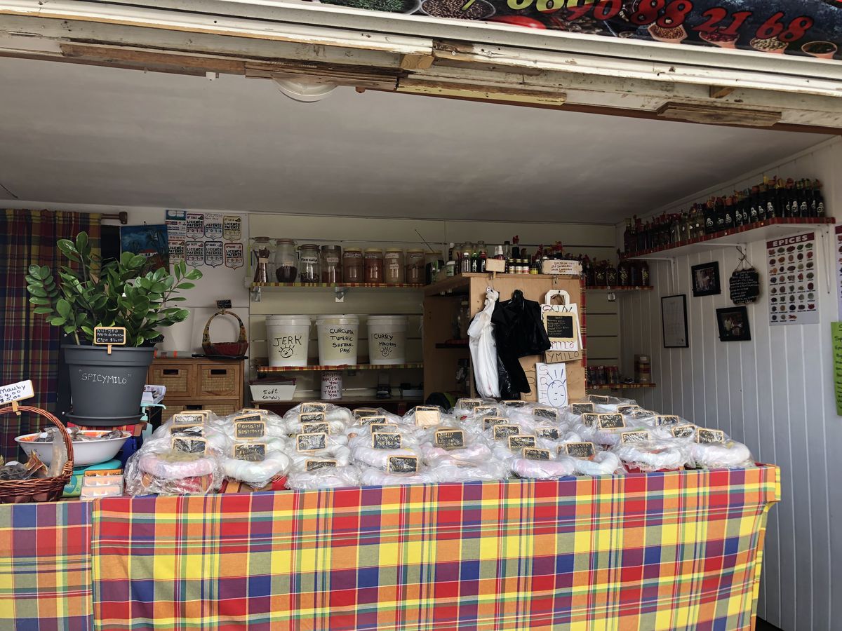An open-air shop with bags of spices beneath chalkboard signs