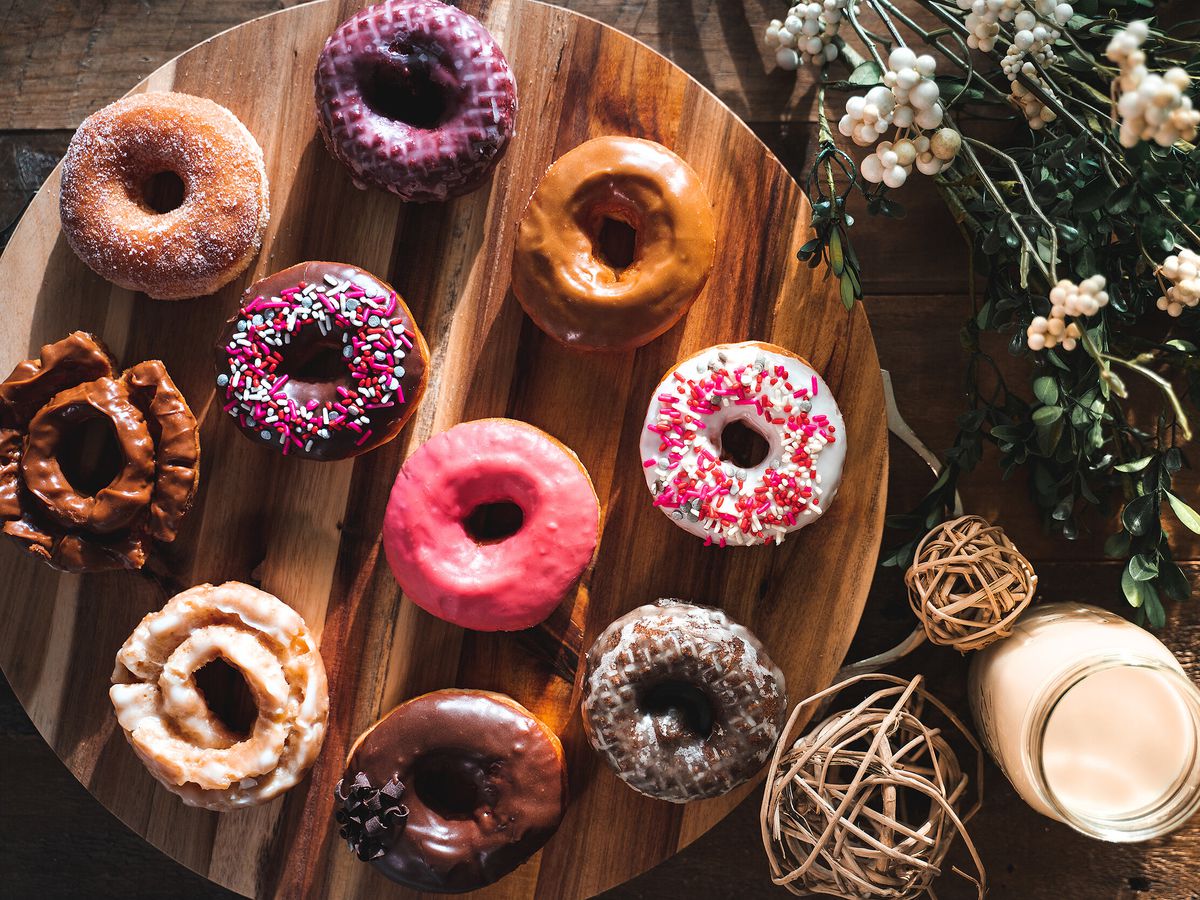 A bunch of frosted doughnuts on a wooden circle tray.