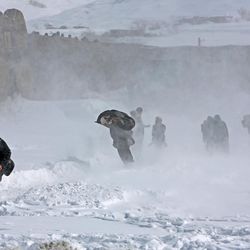 Afghans take cover from snow blowing after an avalanche, in the Paryan district of Panjshir province, north of Kabul, Afghanistan, Friday, Feb. 27, 2015. The death toll from severe weather that caused avalanches and flooding across much of Afghanistan has jumped to more than 200 people, and the number is expected to climb with cold weather and difficult conditions hampering rescue efforts, relief workers and U.N. officials said Friday. 