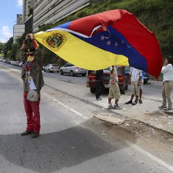 An anti-government demonstrator waves a Venezuelan flag in the middle of the street to protest the government of Venezuela's President Nicolas Maduro in Caracas, Venezuela, Sunday, Aug. 6, 2017. Months of protests are fueled by widespread anger over food shortages, triple-digit inflation and high crime.