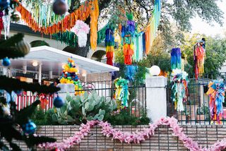 A fence with pink garlands and colorful tinsel hanging from trees