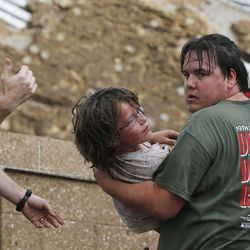 A child is carried from the rubble of the Plaza Towers Elementary School following a tornado in Moore, Okla., Monday, May 20, 2013. A tornado as much as half a mile (.8 kilometers) wide with winds up to 200 mph (320 kph) roared through the Oklahoma City suburbs Monday, flattening entire neighborhoods, setting buildings on fire and landing a direct blow on an elementary school. (AP Photo/Sue Ogrocki)