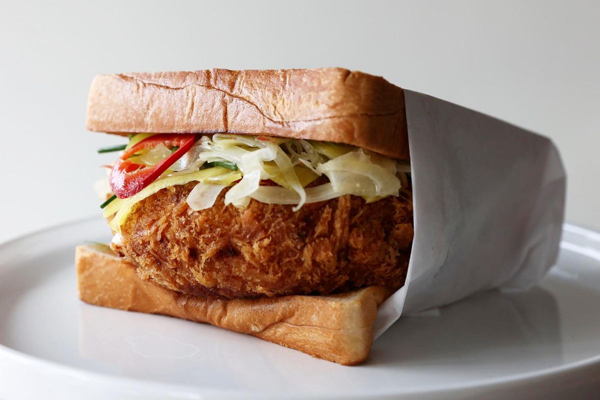 A fried chicken sandwich between two pieces of white bread.