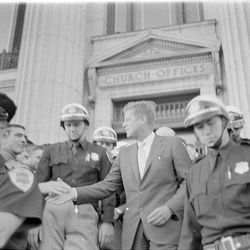 John F. Kennedy leaves the LDS Church Administration Building on South Temple flanked by troopers from the Utah Highway Patrol in 1960.