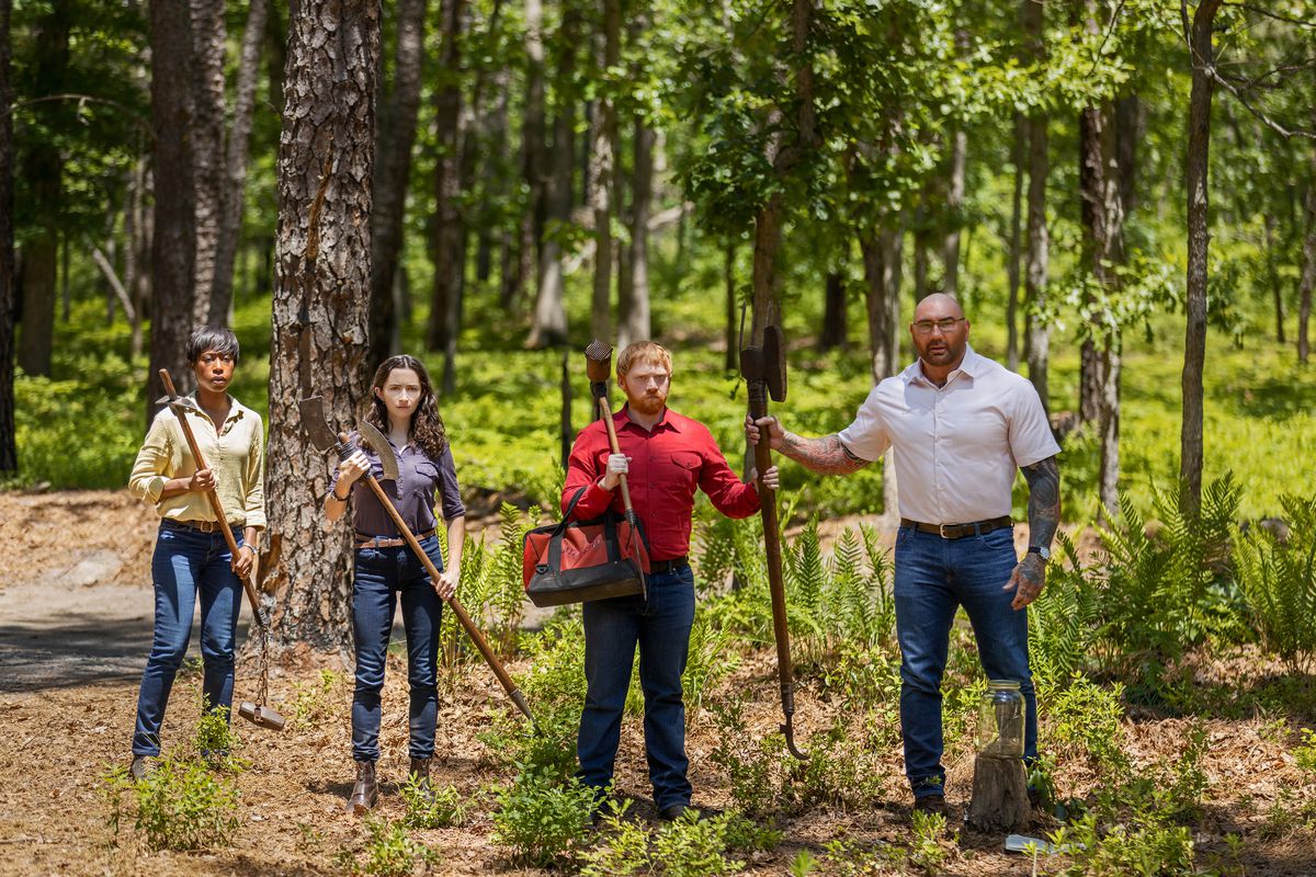 Sabrina (Nikki Amuka-Bird), Adriane (Abby Quinn), Redmond (Rupert Grint), and Leonard (Dave Bautista) standing in a row in the forest in Knock at the Cabin