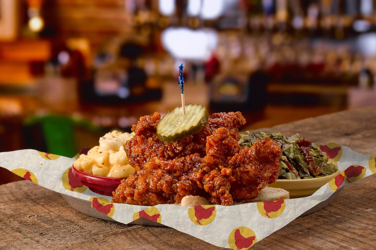 A basket of jumbo hot chicken tenders with a side of mac and cheese and collards