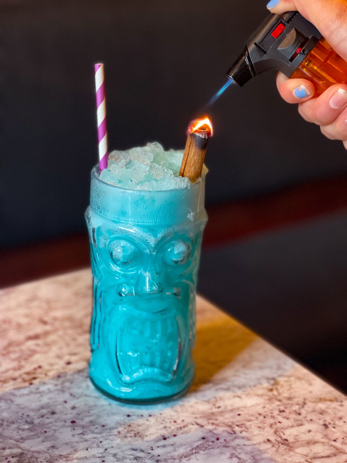 A blue cocktail in a clear tiki glass
