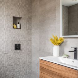 The first-floor bath doubles as powder room and guest bathroom, complete with a corner shower. Textured tile creates a waterproof accent wall. 