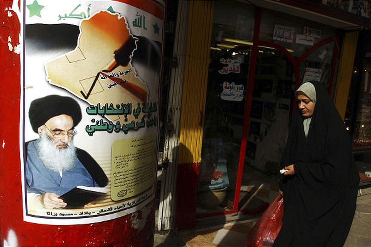 In this Nov. 23, 2004 file photo, an Iraqi woman passes a poster with a religious ruling, issued by Shiite cleric Grand Ayatollah Ali al-Sistani, seen on the posterto encourage people to vote in Iraq's upcoming elections in Baghdad.
