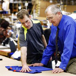 Cade Osborn talks with his father, Dave Osborn, about a new style as they work on the Osborn Apparel production floor.