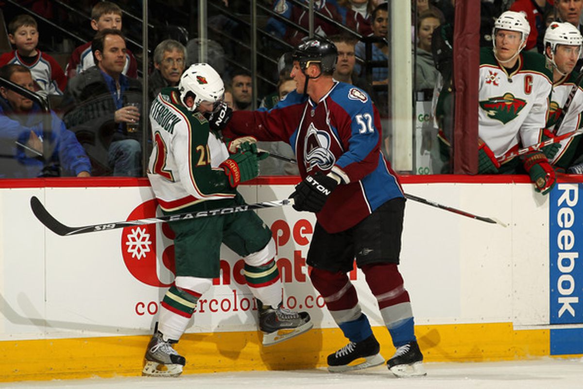 DENVER - DECEMBER 23, 2010:  Adam Foote #52 of the Colorado Avalanche gets in the face of Minnesota Wild #22 Cal Clutterbuck as captain Mikko Koivu (R) #9 soils his hockey pants. (Photo by Doug Pensinger/Getty Images)