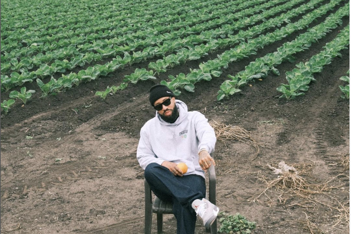 A man sitting in front of a row of crops.