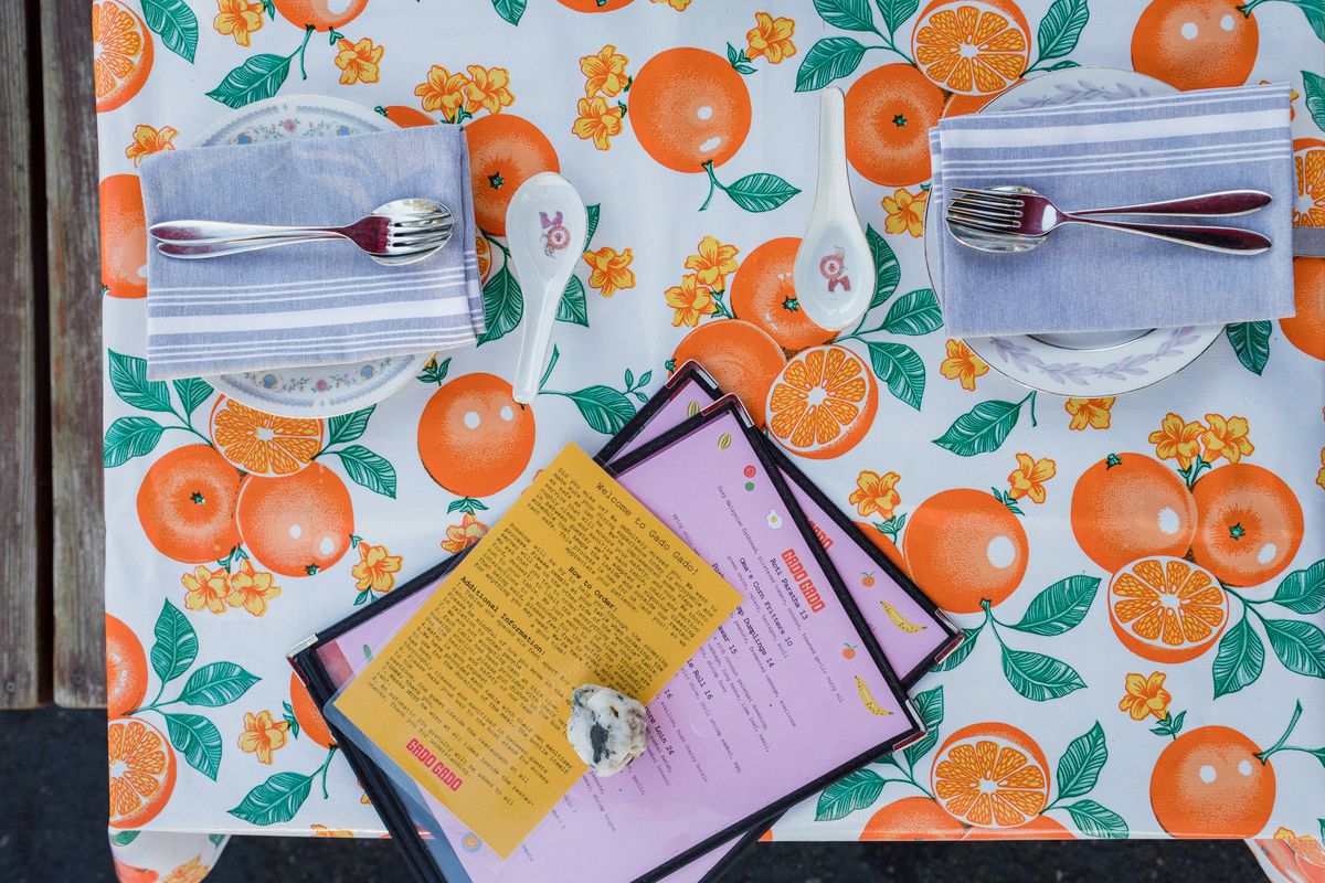 A table set with plates and silverware and menus on an oilcloth tablecloth