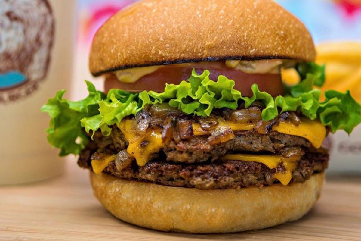 A plant-based double patty burger on a wooden table.