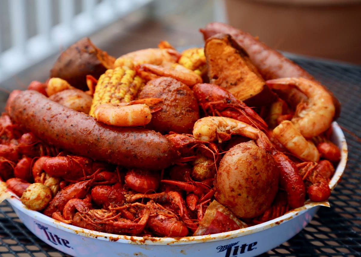 boiled crawfish, shrimp, corn, and sausage in a silver tray.