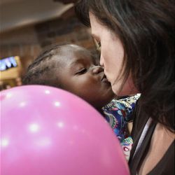 Michelle Gordon kisses her newly adopted Haitian daughter, Avrie, after they arrived at Salt Lake City International Airport Monday.