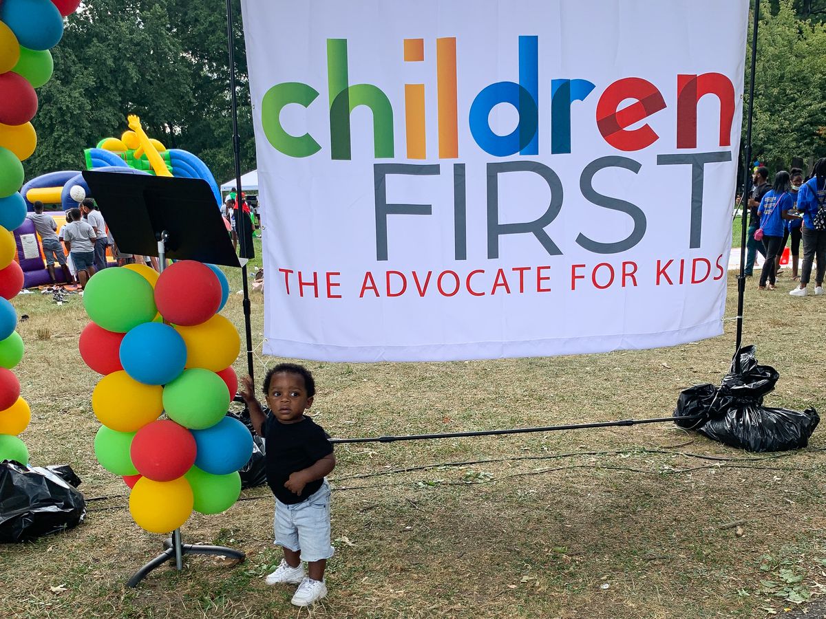 A young boy stands next to a sign for Children First, a nonprofit child advocacy group formerly named Public Citizens for Children and Youth based in Philadelphia.