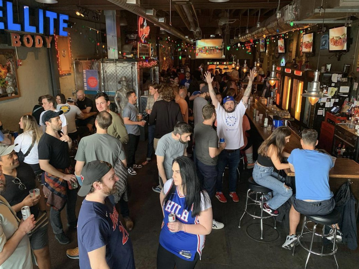 A crowd of sports fans in Philadelphia Sixers jerseys at a bar. 