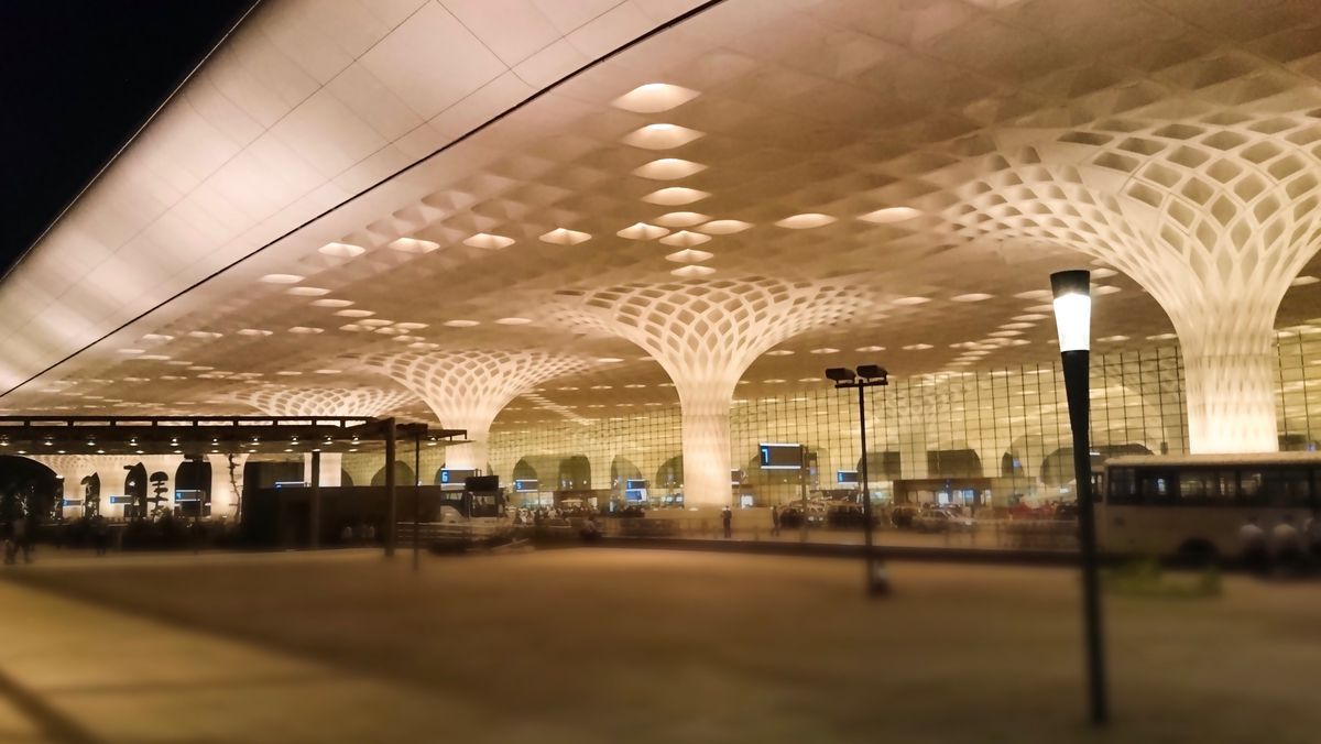The exterior of the Chhatrapati Shivaji International Airport in Mumbai, There are columns that rise up into a mushroom shape towards a canopy.