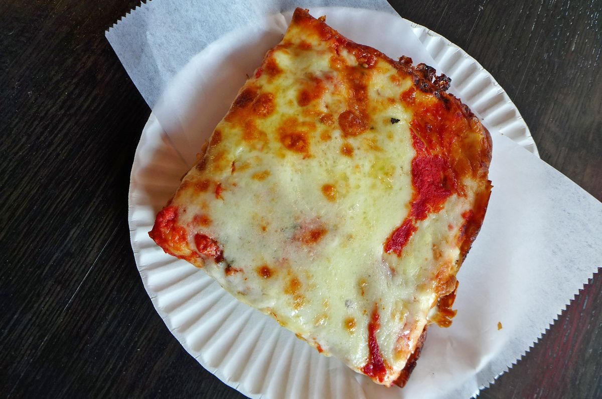 A square slice with bright red sauce and ivory cheese.