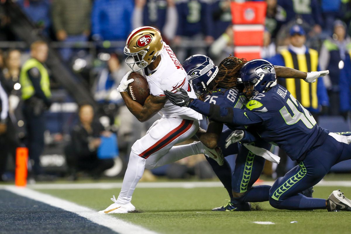 San Francisco 49ers running back Raheem Mostert rushes for a touchdown against Seattle Seahawks cornerback Shaquill Griffin and defensive back Lano Hill during the fourth quarter at CenturyLink Field.