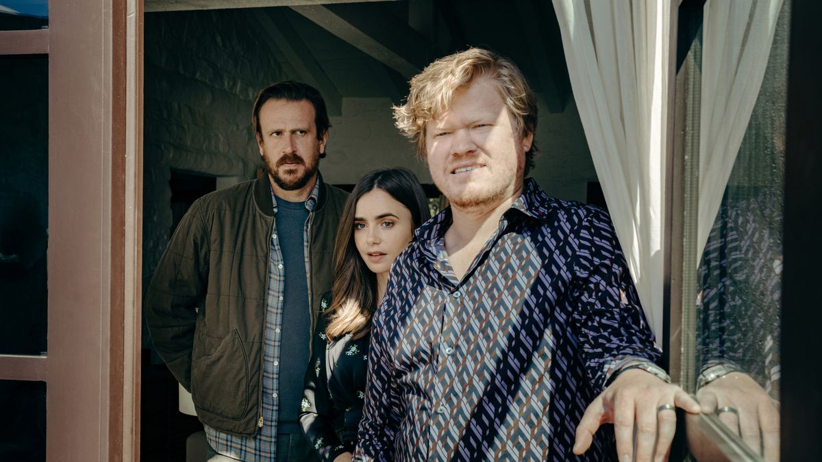 Jesse Plemons, Lilly Collins, and Jason Segel stand at a window in the Netflix movie Windfall.